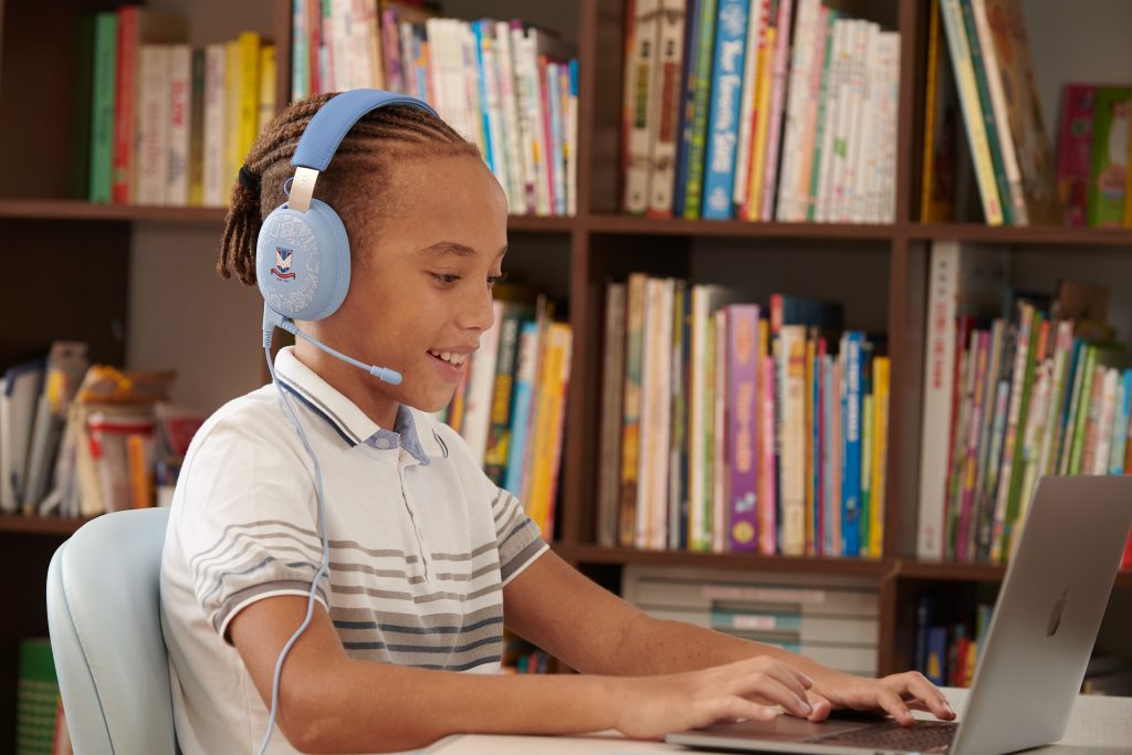 A person wearing headphones and sitting in front of a book shelf

Description automatically generated with low confidence